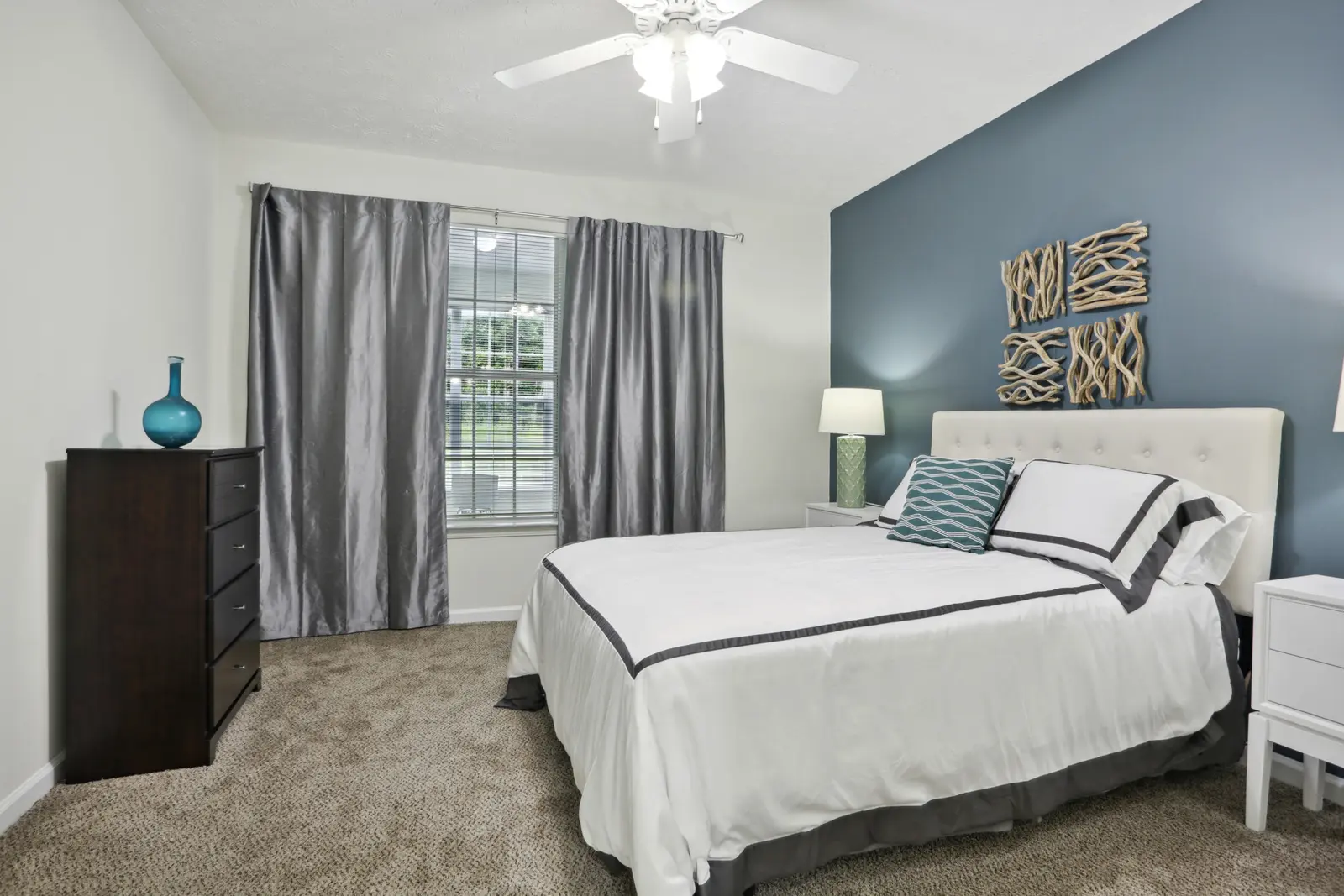 Carpeted bedroom with queen bed, two bedside tables and dresser